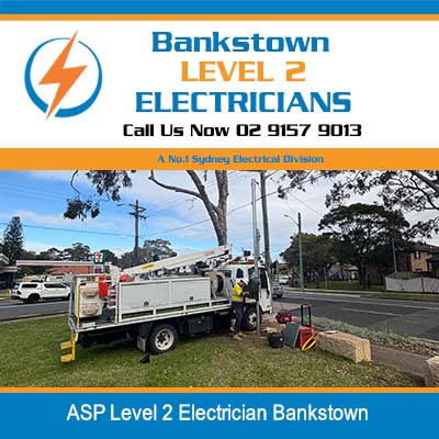 Level 2 electrician crew working on power pole with service truck on suburban street in Bankstown